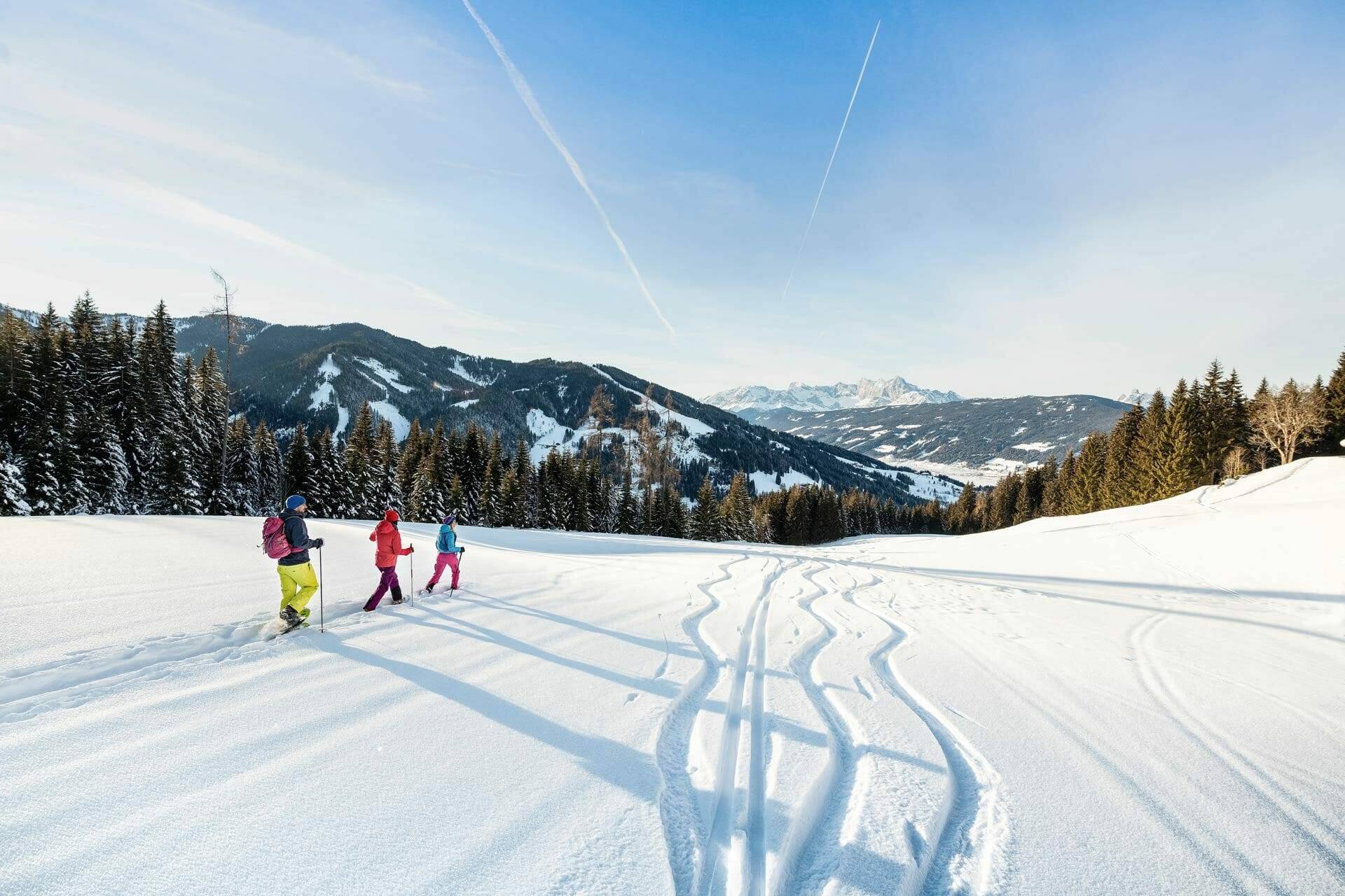 Familie beim Schneeschuhwandern in den Bergen Flachaus